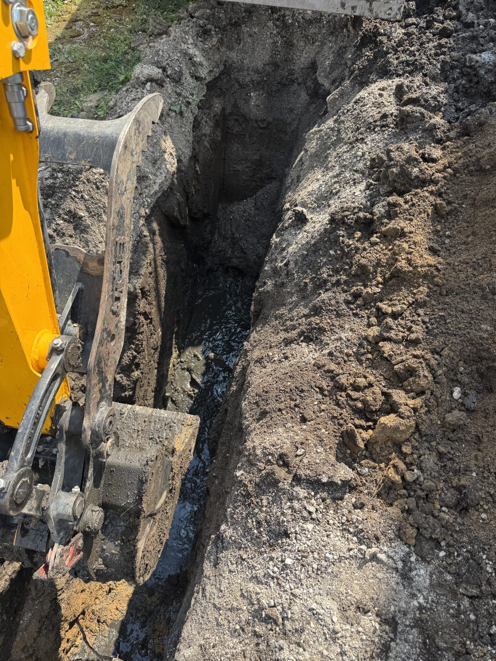 Water line repair excavation with exposed pipe and groundwater in trench for residential service