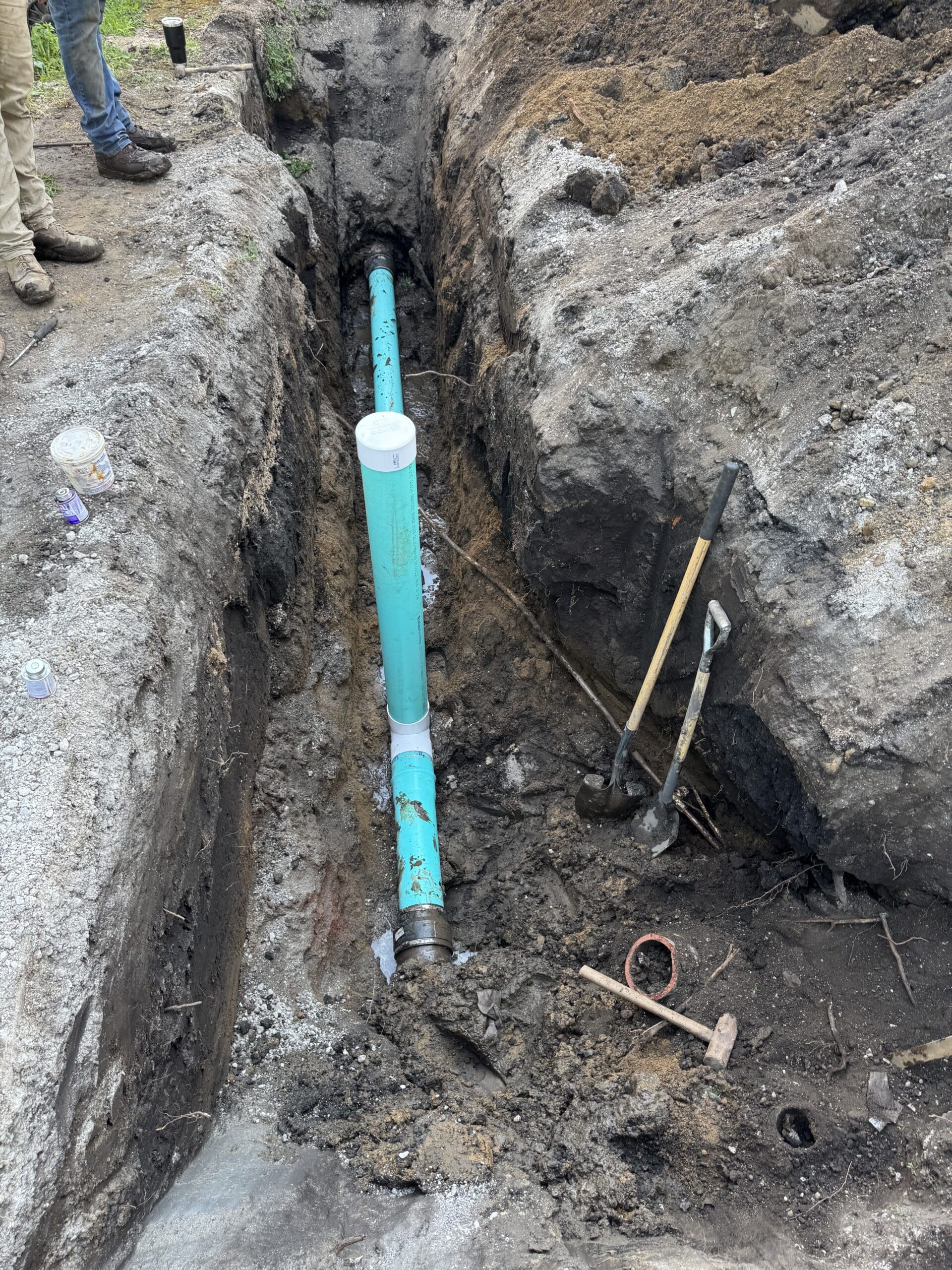 Sewer line repair trench with exposed pipe during underground service work
