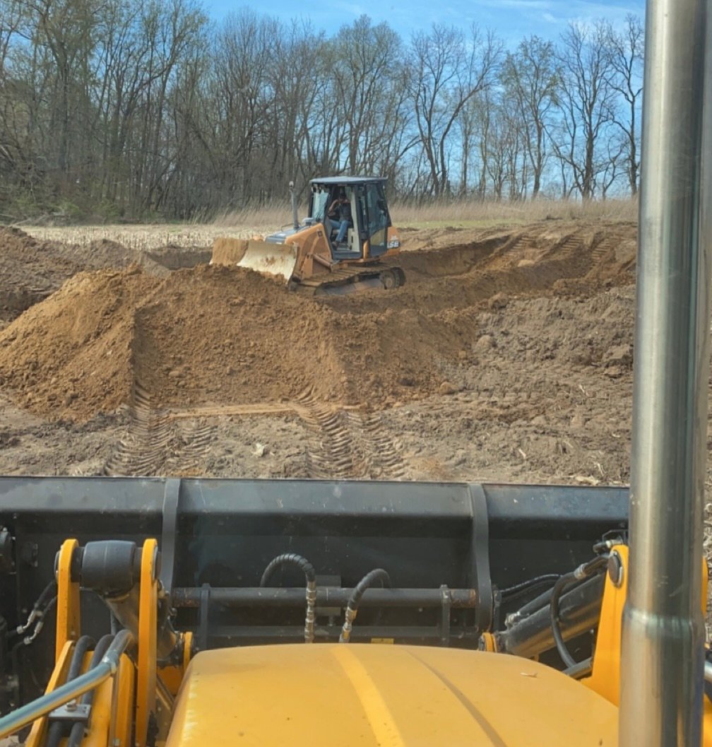 Excavation contractor operating bulldozer to grade and move soil for residential site preparation