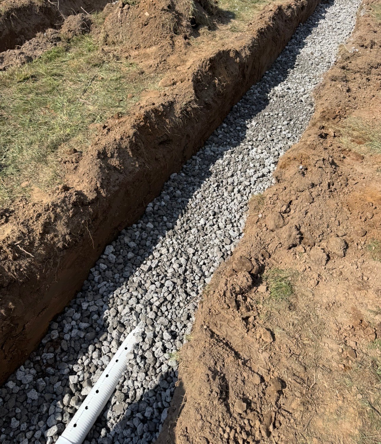 Septic system drain field installation with gravel trench and perforated pipe for proper wastewater drainage and soil filtration